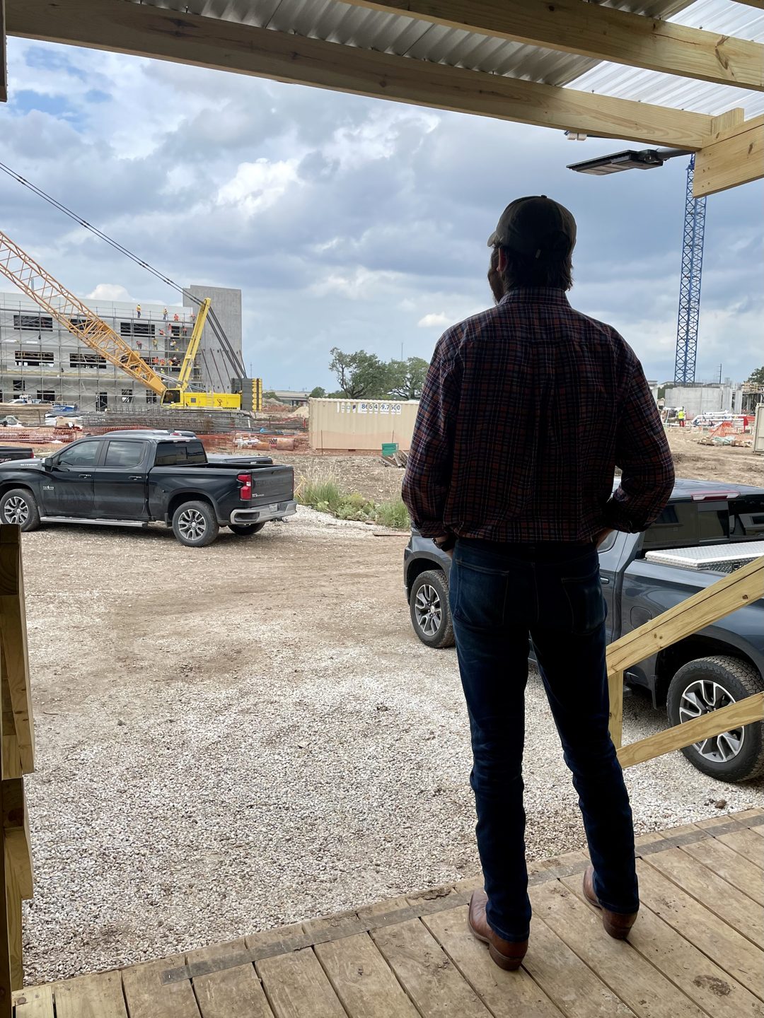 Richard Batson on site overseeing an active large-scale construction project, a crane and building under construction in the background